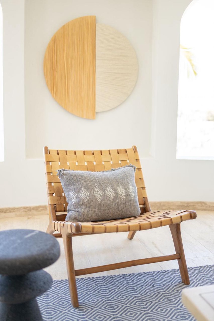 Settle into this handcrafted woven chair with its plush accent pillow—a serene corner where you can unwind, sip your morning coffee, or simply soak in the tranquil ambiance of your getaway.
