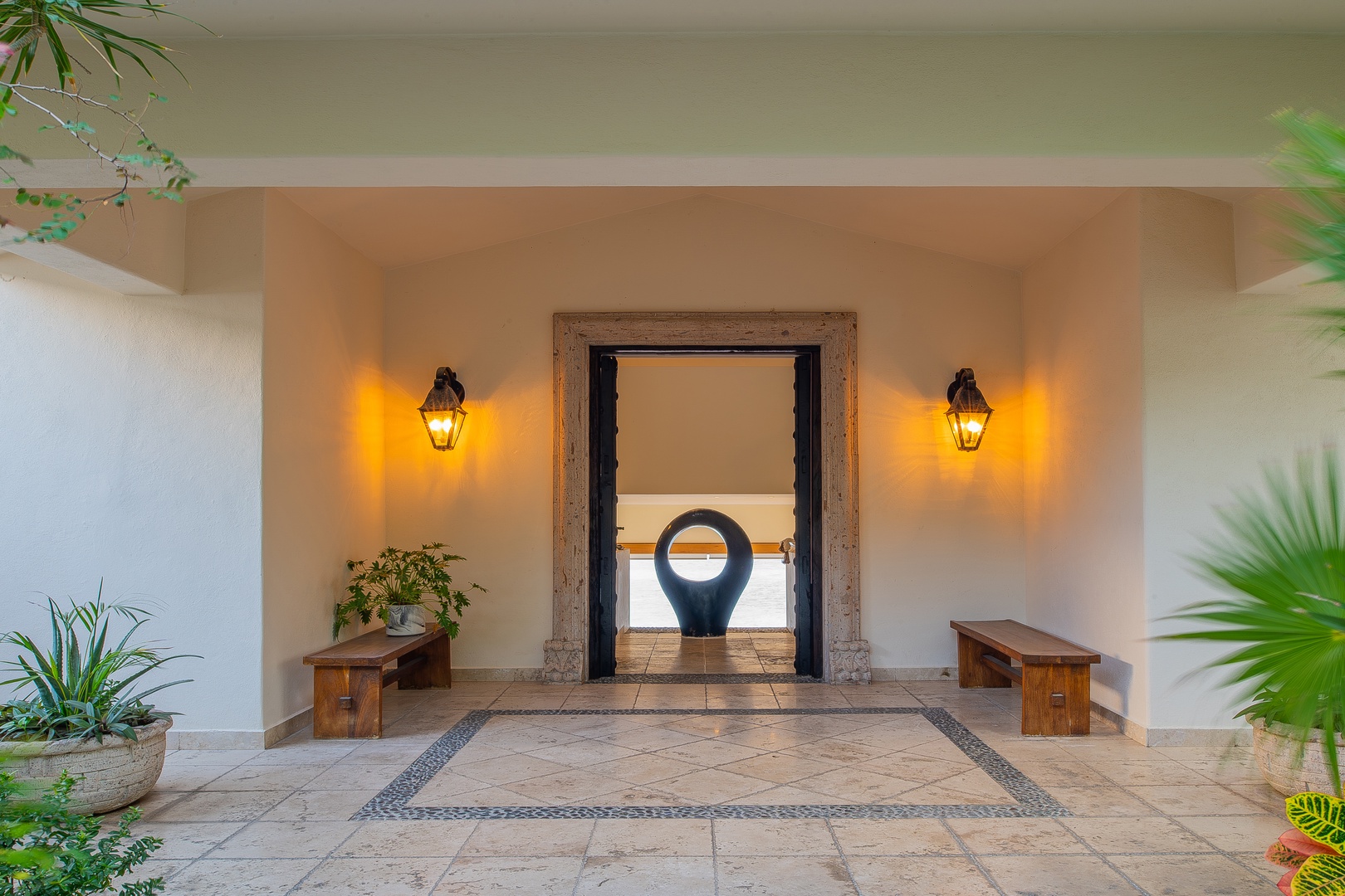 Welcome entrance with stone tiles, warm ambient lighting, and tropical greenery framing the doorway—your getaway begins here.