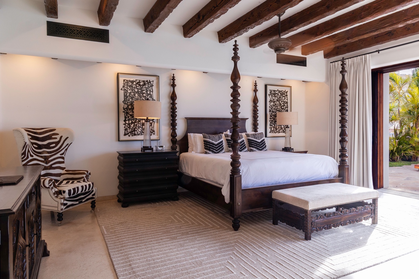 Step into your private sanctuary, where rustic wooden beams frame a stunning four-poster bed dressed in crisp linens. Zebra-print accents and carved décor add exotic charm to this restful retreat.