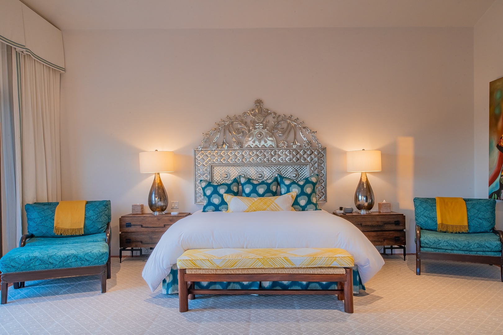 Sink into crisp linens and plush pillows in your serene bedroom, where vibrant accents and an ornate headboard create a space that feels both luxurious and welcoming.