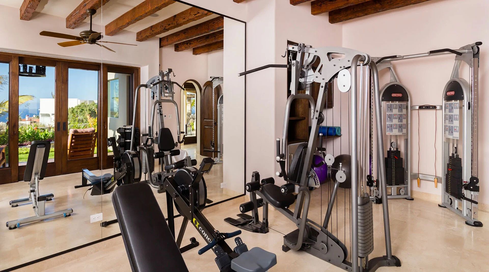 Your private fitness center awaits with professional-grade equipment, natural light, and exposed beam ceilings—perfect for energizing workouts with stunning outdoor views.