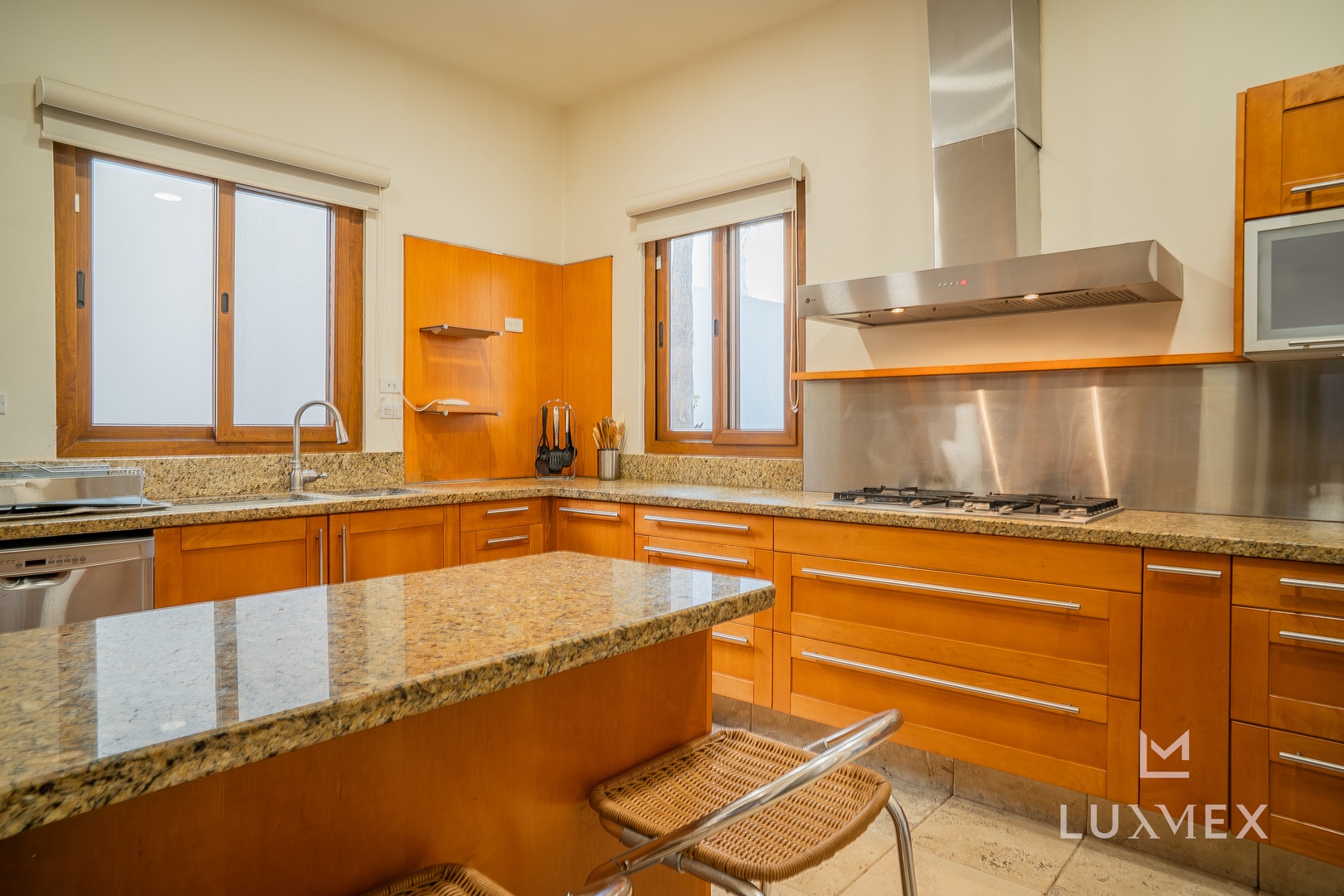 Your fully-equipped kitchen awaits with granite counters, stainless appliances, and warm orange cabinetry perfect for preparing memorable meals.