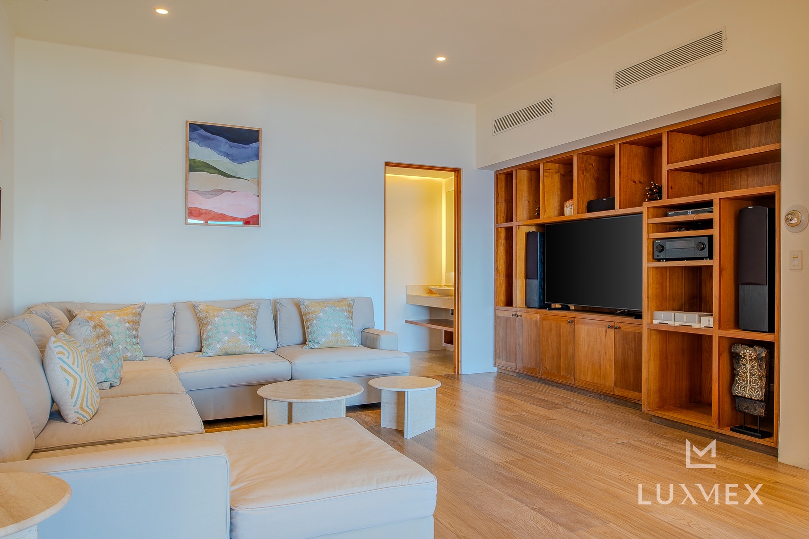 Unwind in your spacious living room featuring plush seating, warm wood entertainment center, and modern climate control for ultimate comfort.