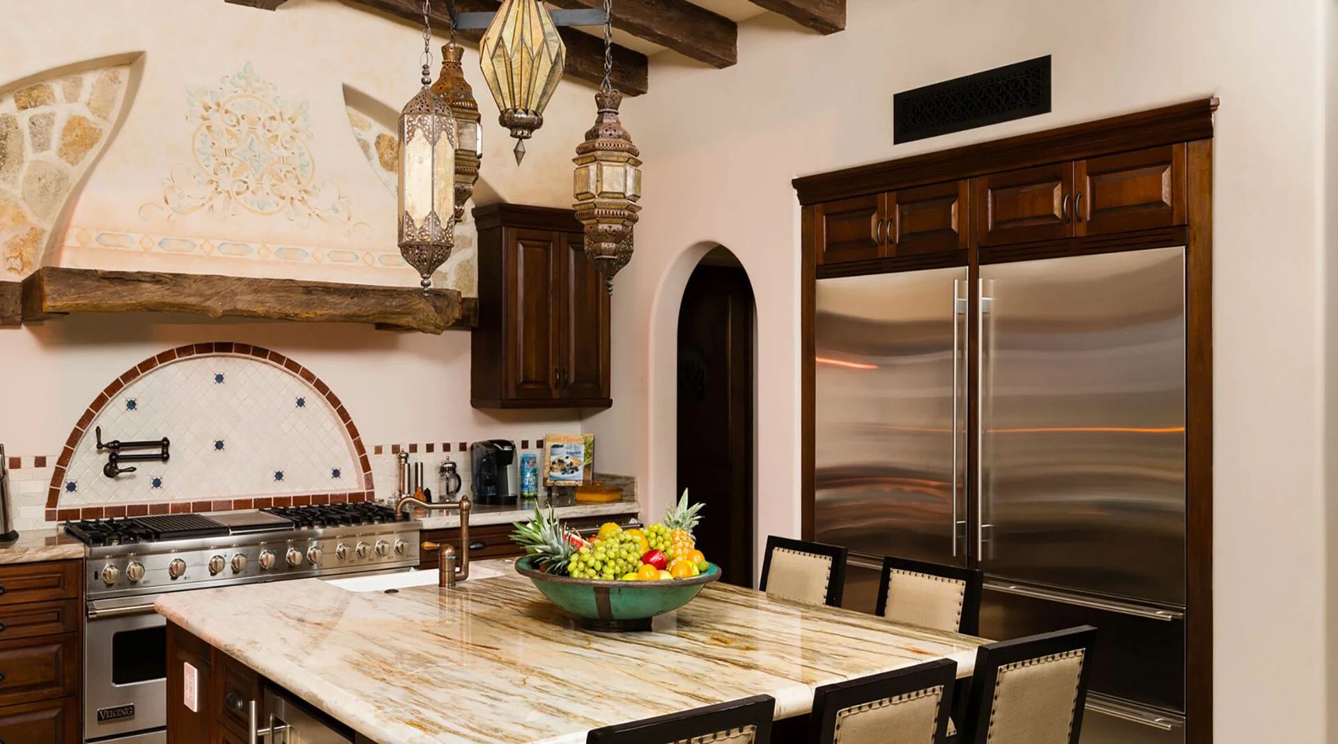 Your gourmet kitchen invites you to gather and create, with rich wood cabinetry, professional-grade appliances, and elegant hanging lanterns casting warm ambiance over the spacious marble island.