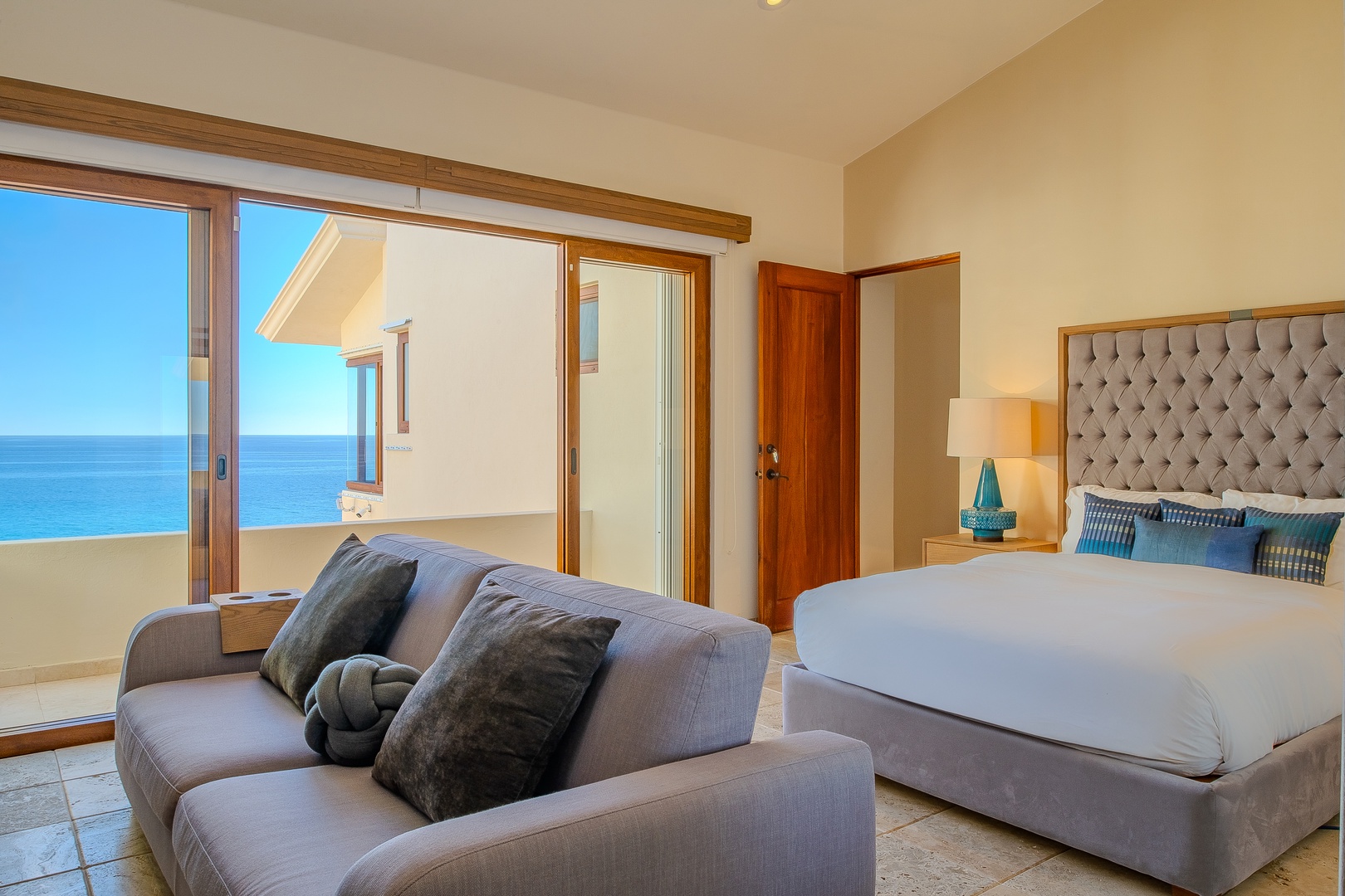 Wake up to stunning ocean vistas through your floor-to-ceiling windows, where plush bedding and a cozy lounge area invite you to unwind while soaking in the endless blue horizon.