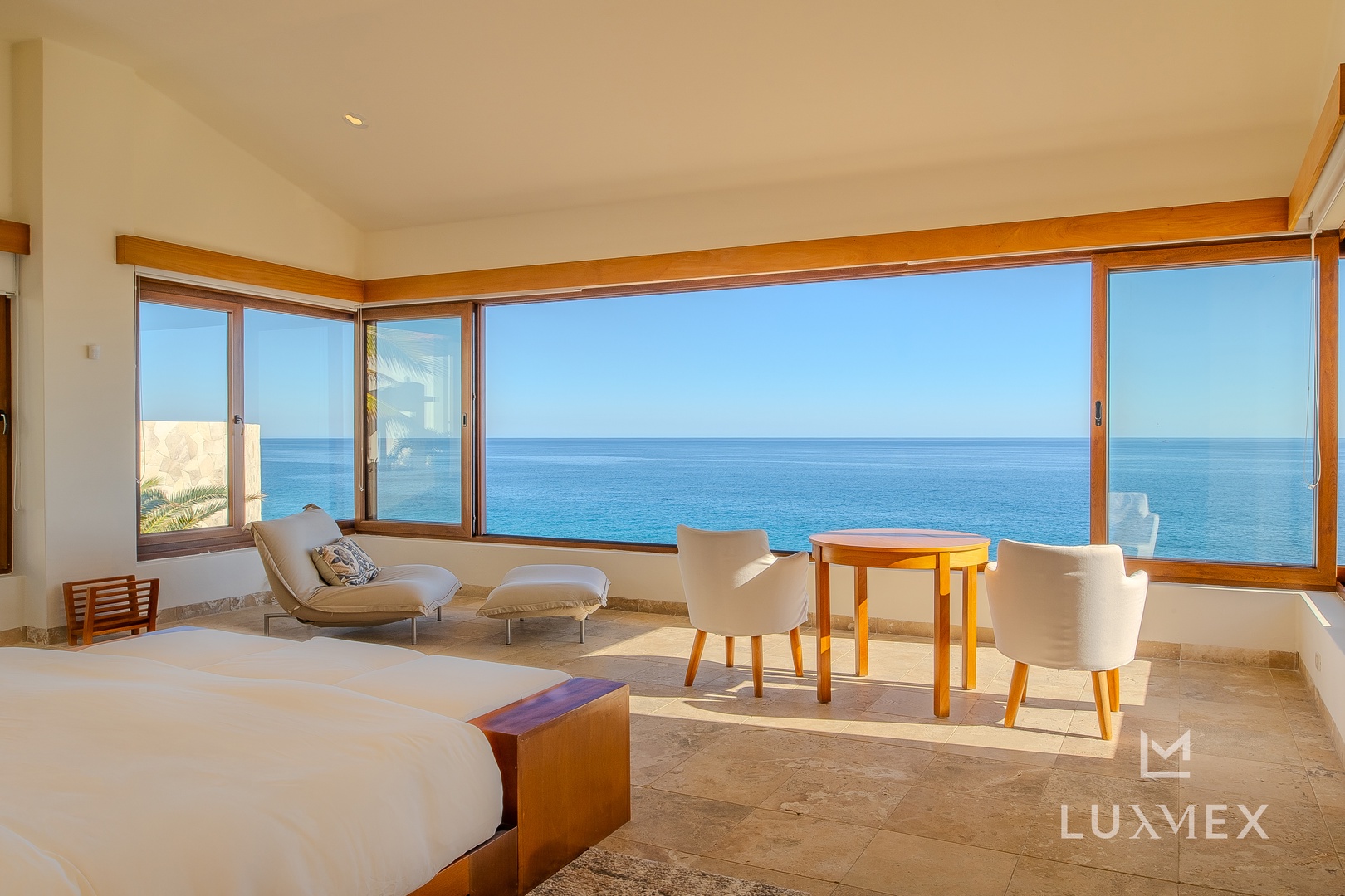 Wake up to endless ocean views through floor-to-ceiling windows in your luxurious bedroom retreat with modern seating area.