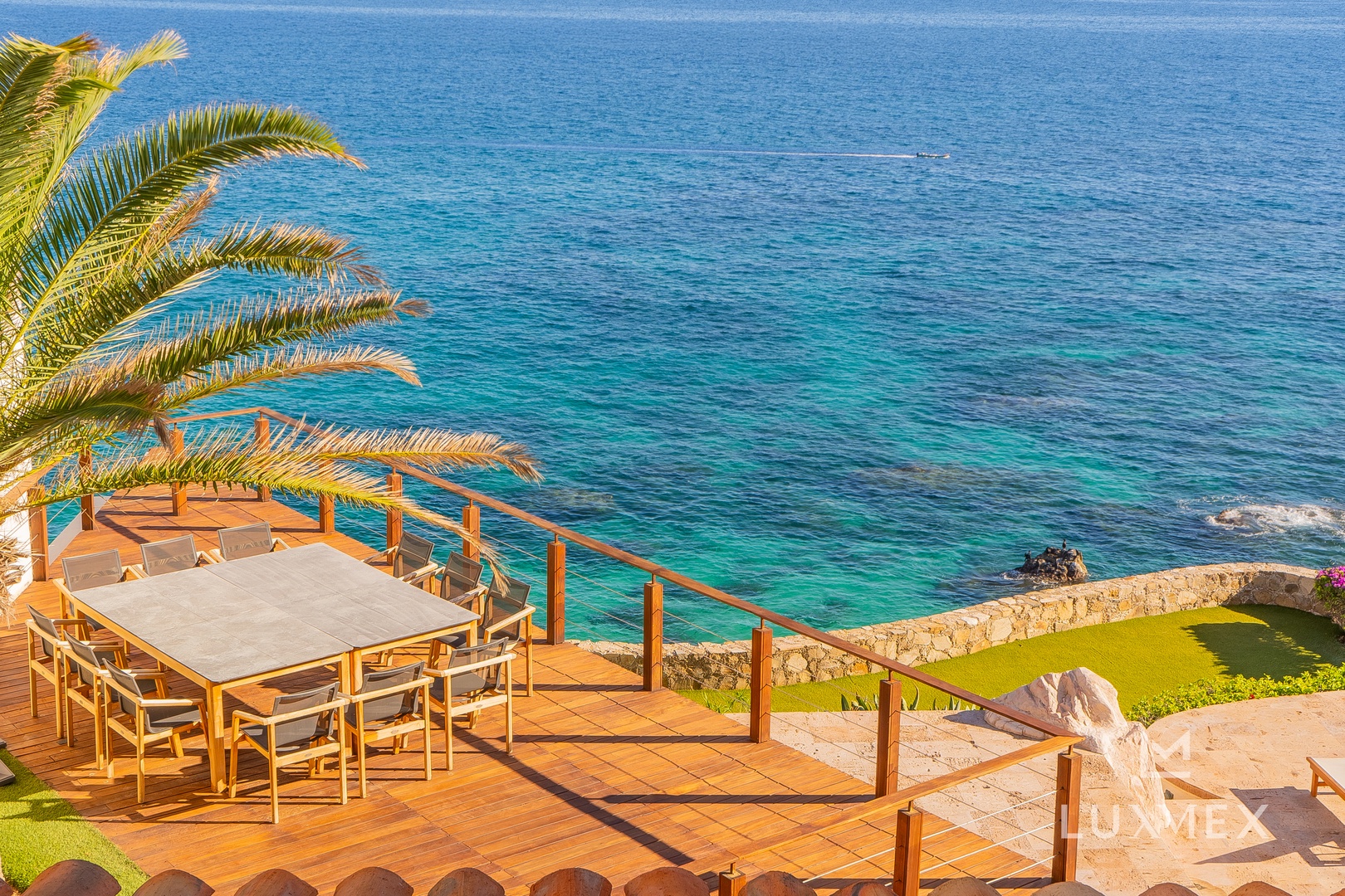 Stunning seaside terrace overlooks crystal-clear turquoise waters, perfect for al fresco dining with breathtaking ocean views.