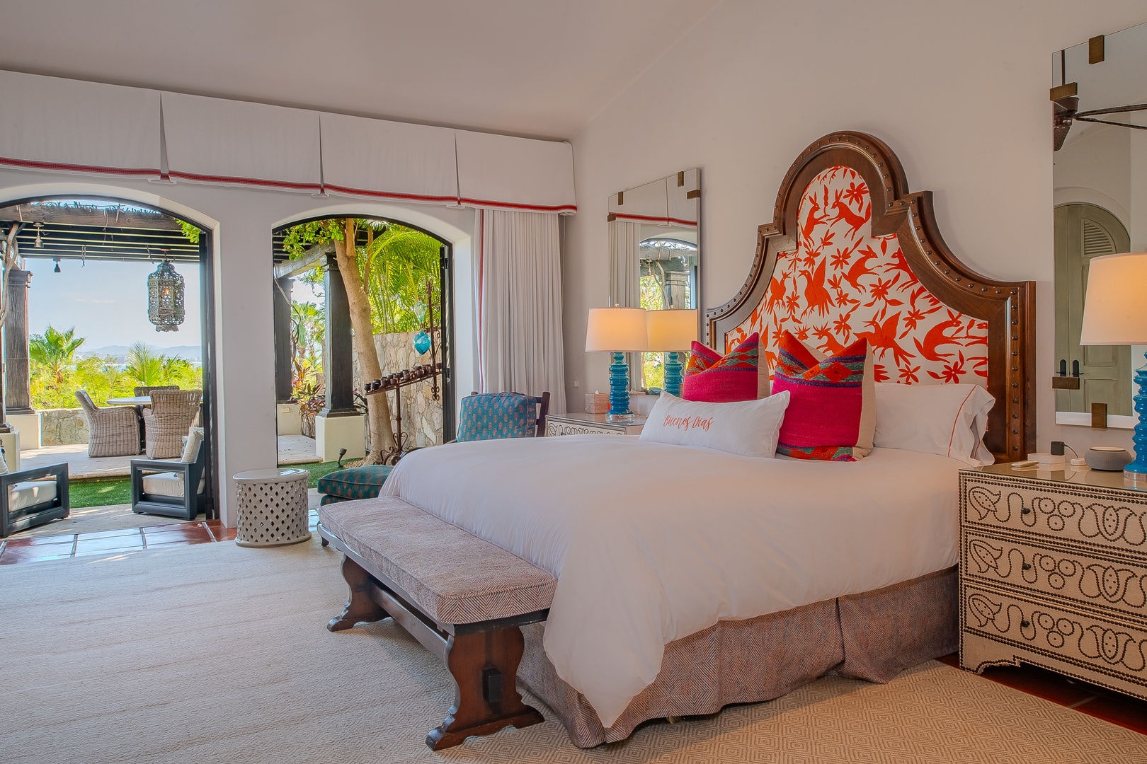 Unwind in your elegant bedroom where tropical breezes meet vibrant design. Wake to garden views through arched doors, relax on plush seating, and sink into crisp linens.