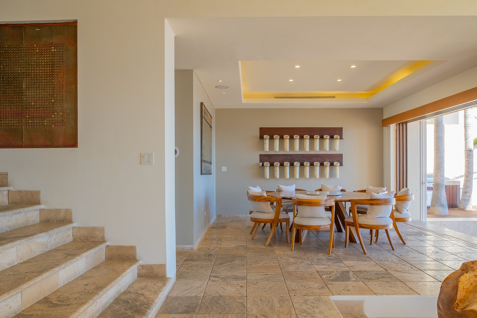 Gather around the beautiful wood dining table where your group can share memorable meals together, with warm ambient lighting and tropical views just beyond the windows.