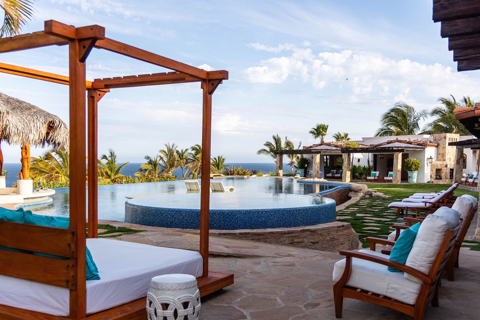 A luxurious infinity pool blends seamlessly with the ocean horizon, framed by tropical palms and shaded lounging areas—your private coastal retreat awaits.