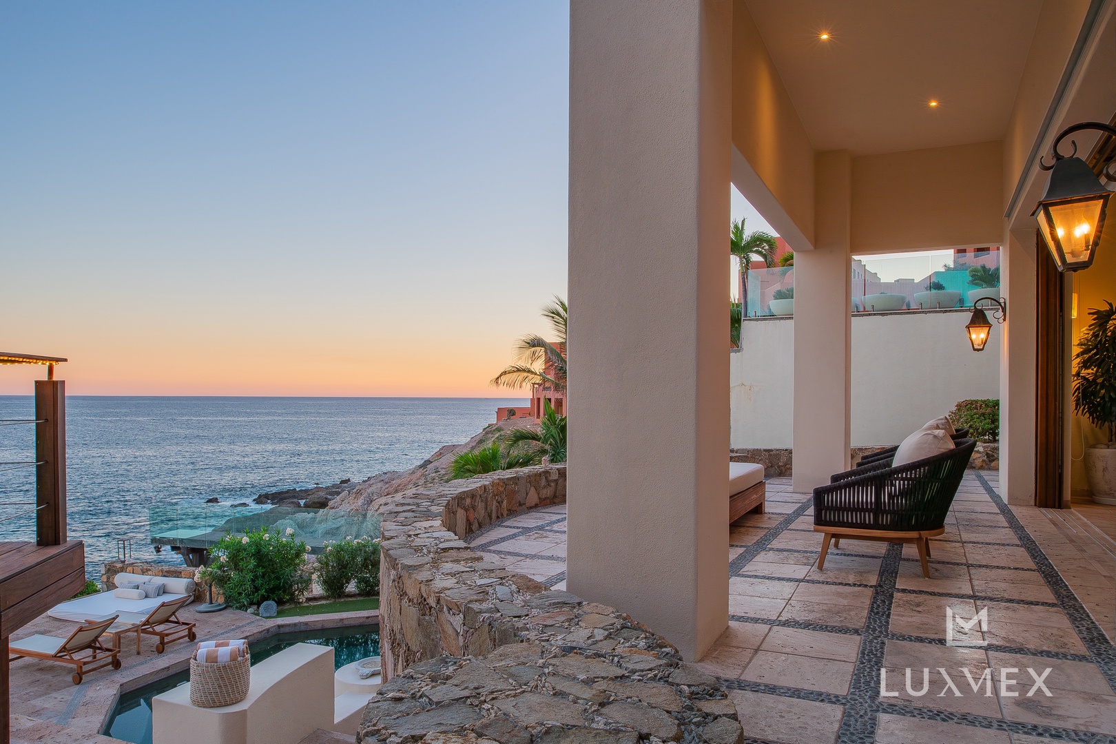 Breathtaking ocean views frame this covered terrace as the sun sets over the horizon, creating the perfect backdrop for evening relaxation.