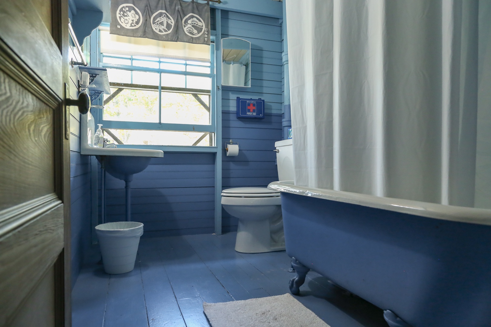 Unwind in your charming blue bathroom with vintage clawfoot tub and nautical touches.