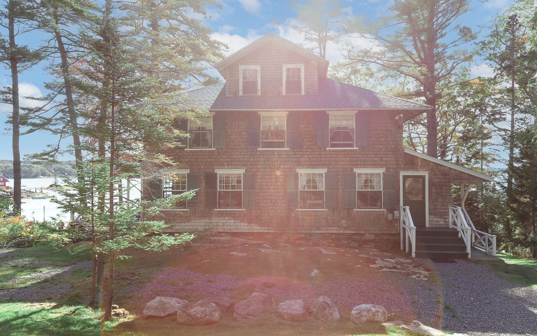 Classic Maine charm awaits at this cedar-shingled cottage, where green shutters and wraparound porches create the perfect waterfront retreat on Linekin Bay.