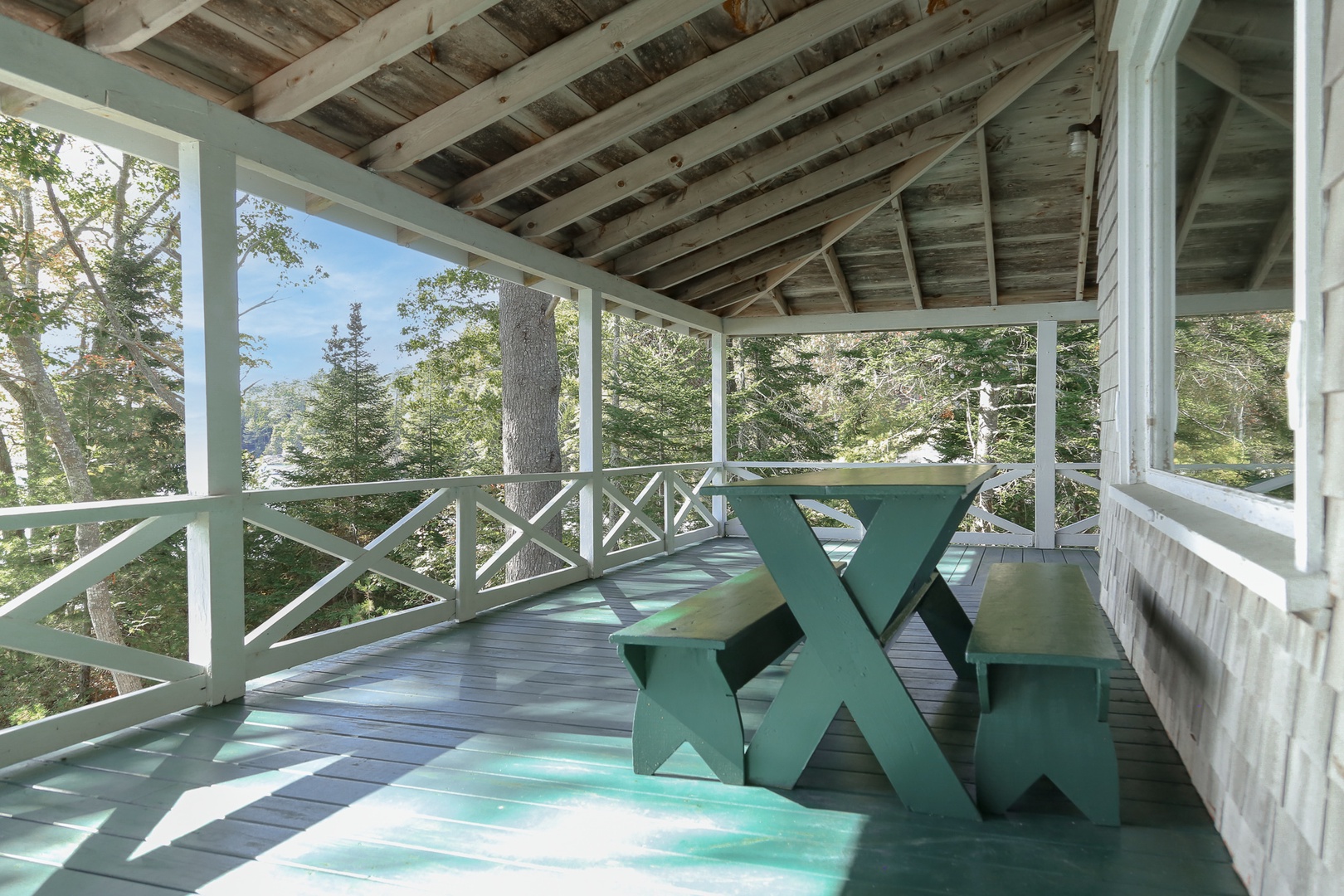 Relax on your private covered porch with rustic charm, enjoying peaceful water views while dining al fresco on the picnic table.