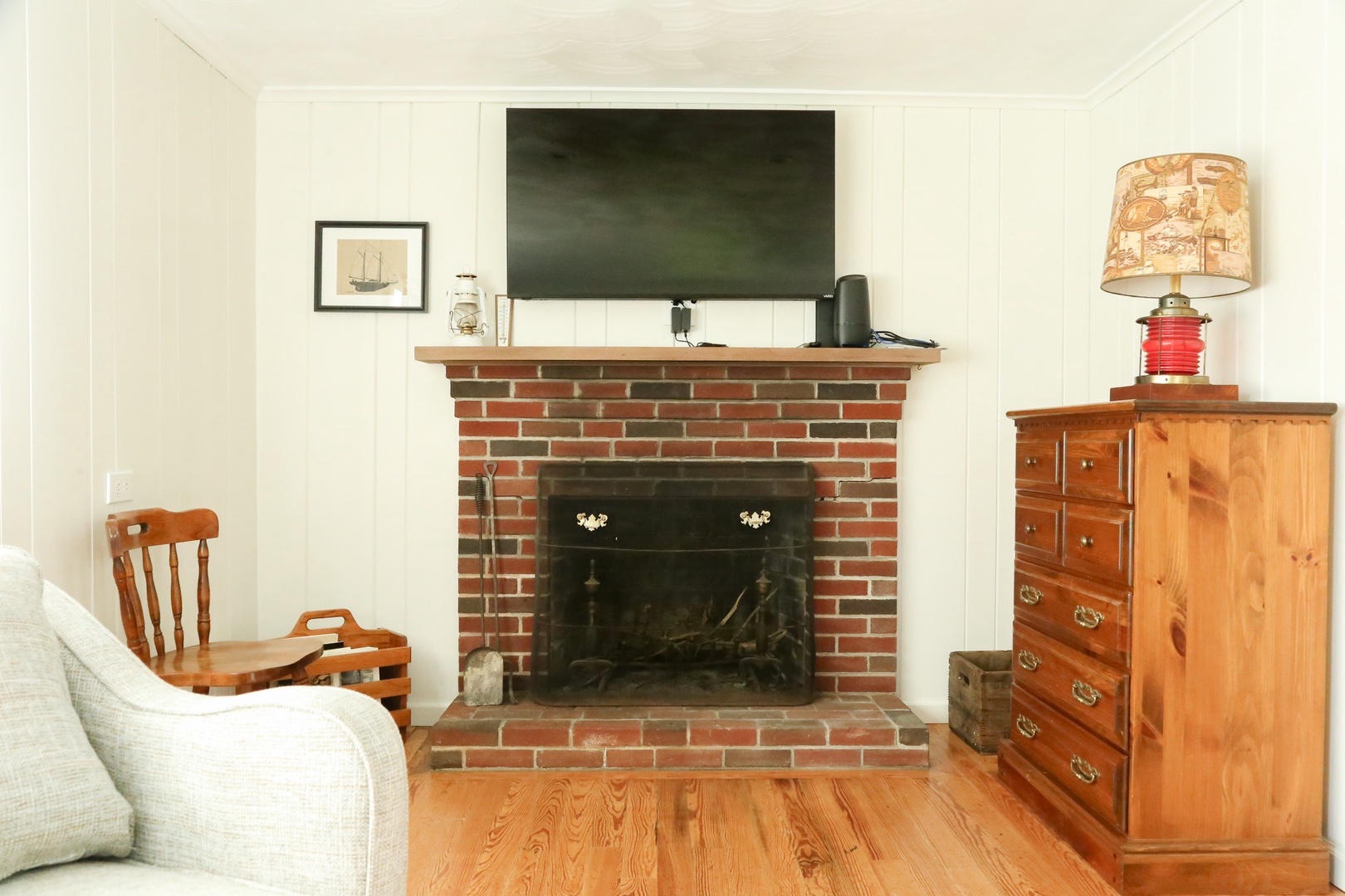 Cozy living room with a charming brick fireplace where you can unwind after a day of adventure. The space features warm wood floors, a comfortable seating area, and coastal-inspired décor that creates the perfect retreat for your stay.