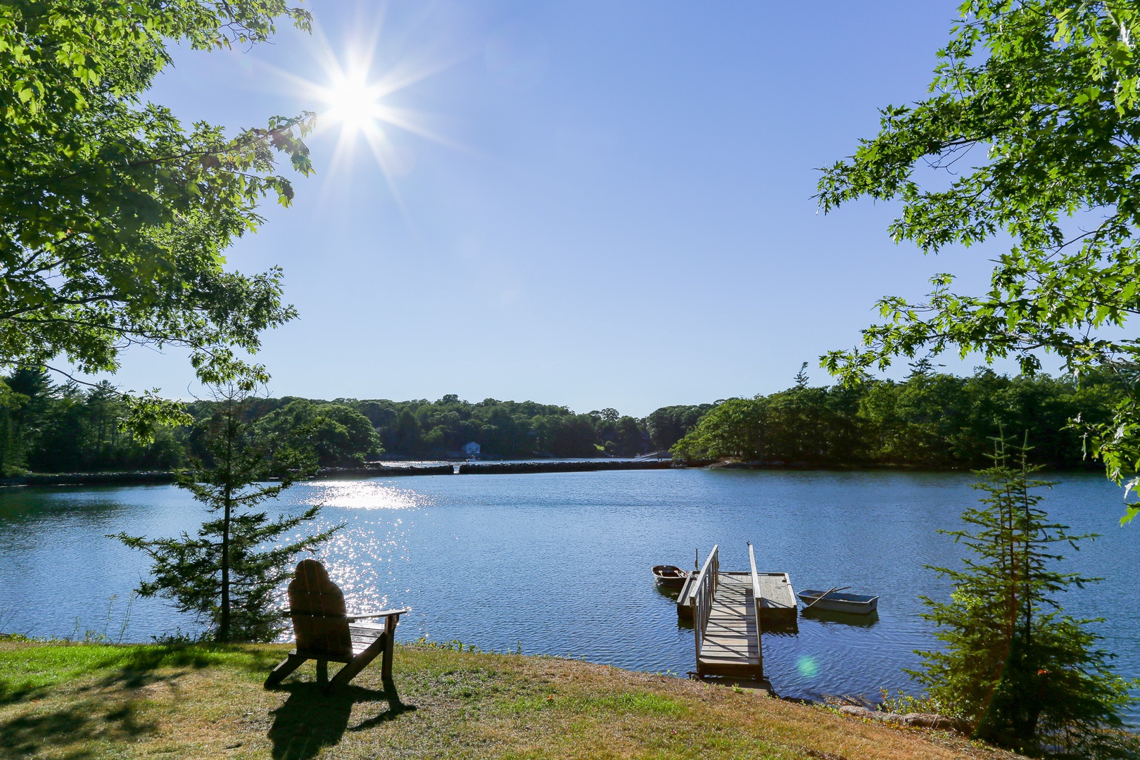 Peaceful waterfront retreat framed by lush greenery, with private dock and boats ready for your waterfront adventures.
