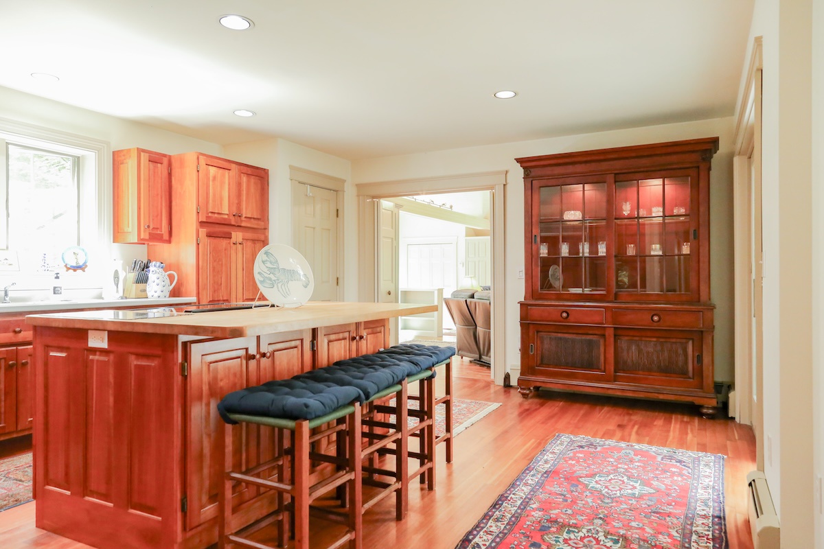 Gather around the inviting kitchen island for morning coffee or meal prep in this warm, light-filled space with rich wood cabinetry and cozy seating for casual dining together.
