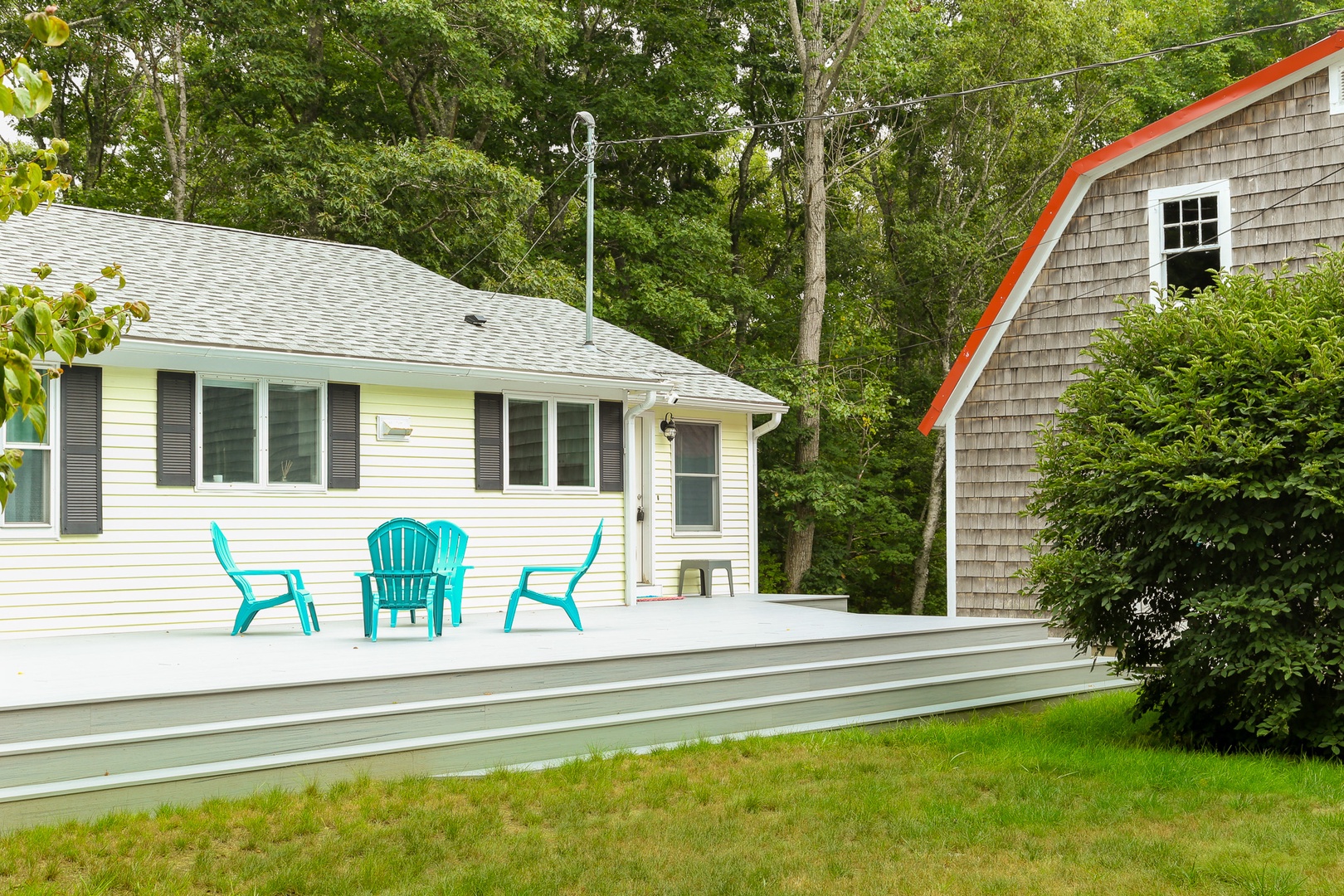 A charming coastal retreat nestled among lush trees with a peaceful deck awaiting your morning coffee or evening conversations under the canopy.