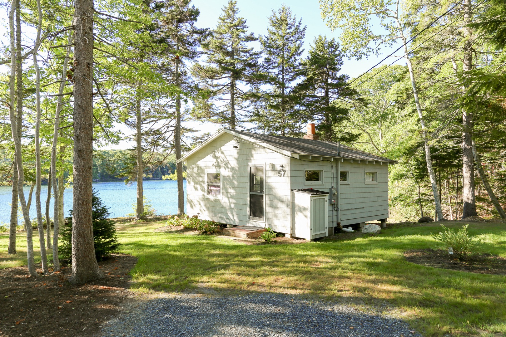 A charming waterfront cottage nestled among towering pines, with peaceful water views and a tranquil natural setting perfect for a relaxing getaway.