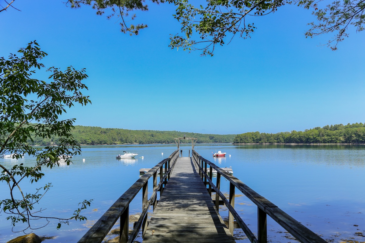 A private dock stretches into the Damariscotta River, framed by lush wooded shorelines—a peaceful spot to take in the natural beauty surrounding the property.