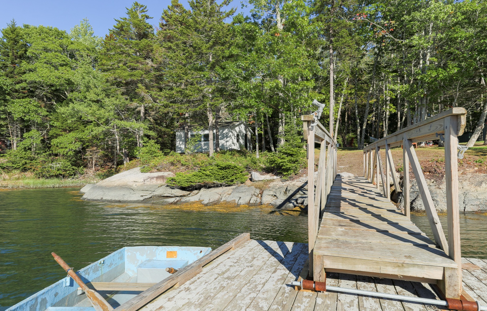 Private dock and rowboat lead to a peaceful waterfront retreat surrounded by lush forest.