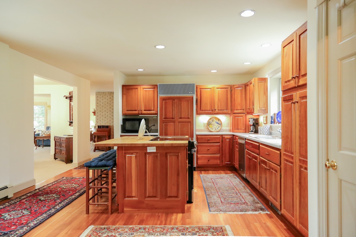 Step into your fully equipped kitchen featuring warm cherry cabinetry, granite counters, and a convenient center island with bar seating for casual meals and conversation.