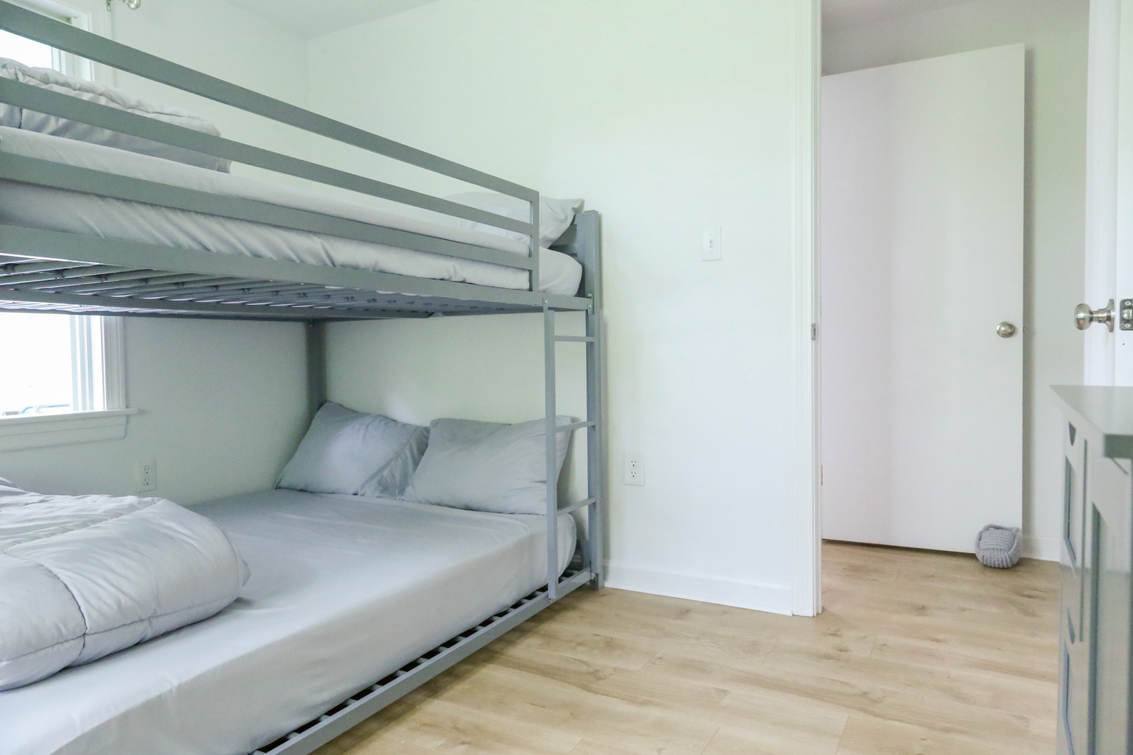 Your room features space-efficient bunk beds dressed in soft, fresh linens—ideal for families or groups traveling together. Light, airy tones and warm wood floors create a welcoming retreat after a day of exploring.