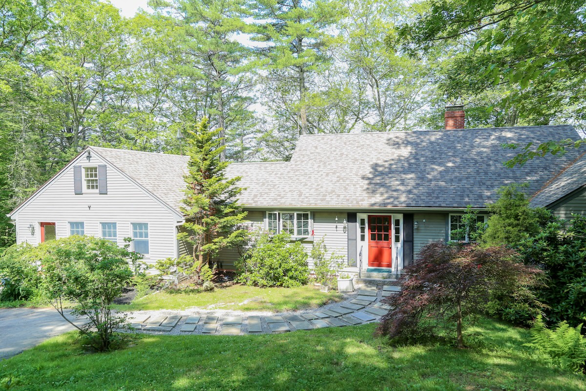 A charming cottage-style rental nestled in a private, wooded setting with a welcoming front entrance and beautifully maintained grounds perfect for a peaceful retreat.