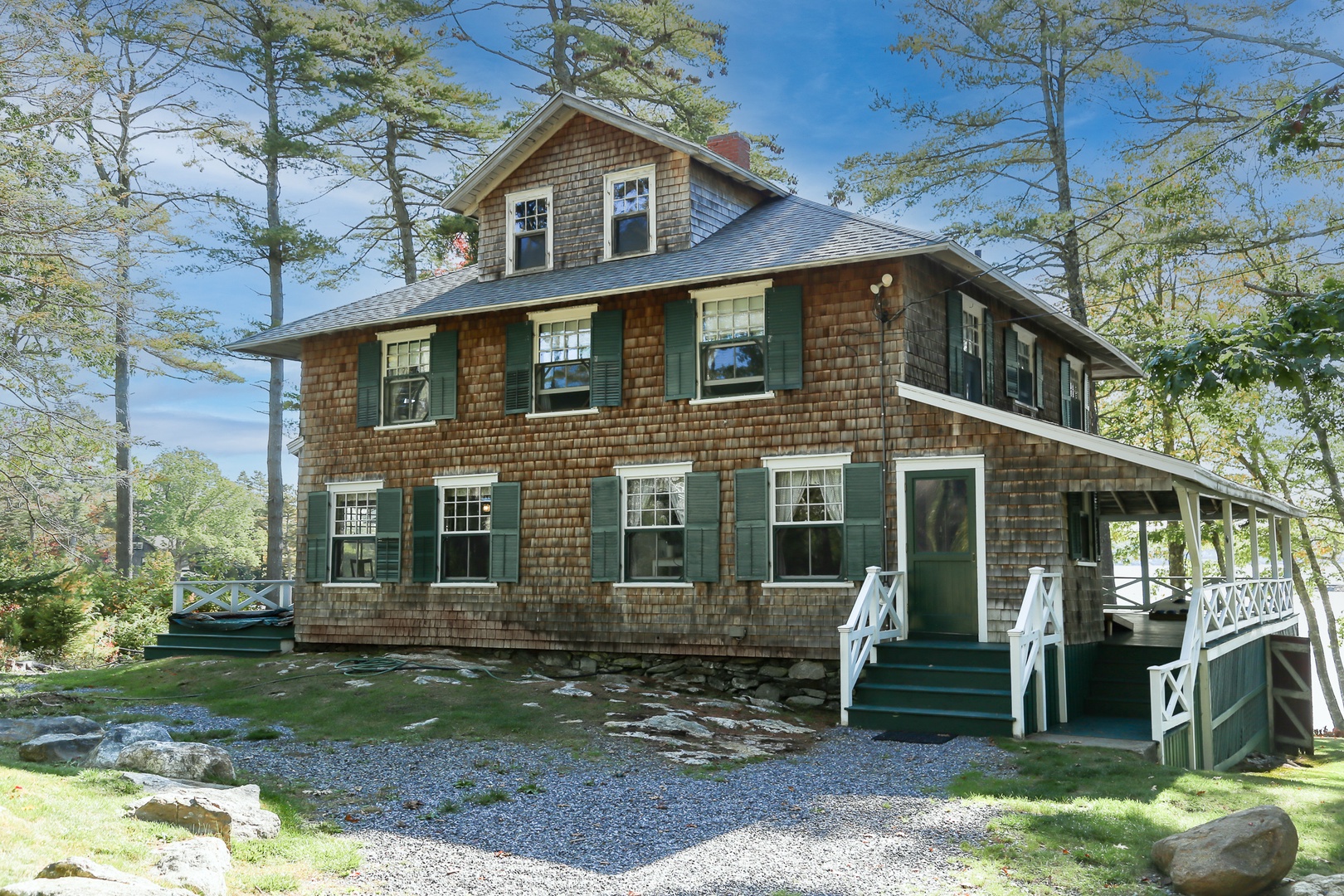 Classic Maine charm awaits at this cedar-shingled cottage, where green shutters and wraparound porches create the perfect waterfront retreat on Linekin Bay.