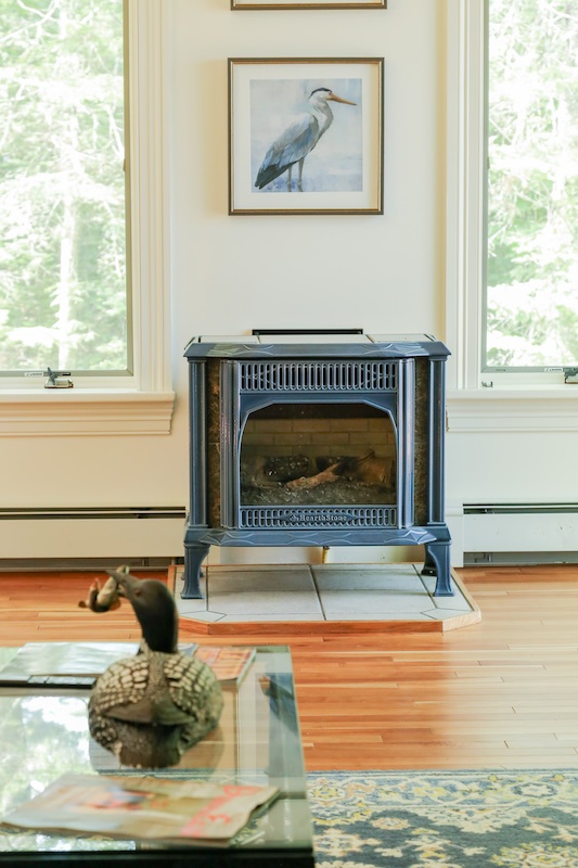 Cozy up by your fireplace in this bright, peaceful living space with garden views and charming coastal touches.