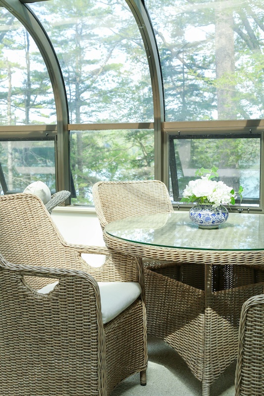 Settle into this sunlit solarium where towering windows frame peaceful forest views. Your morning coffee tastes even better surrounded by nature's tranquility.