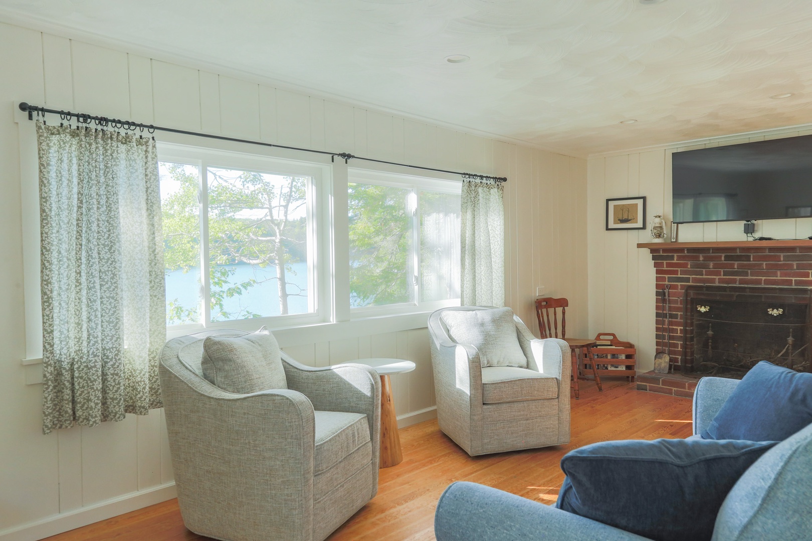 Curl up with a book or morning coffee in your bright, airy living room, where natural light pours through large windows framing peaceful water views. The cozy fireplace and comfortable seating invite you to relax and unwind.