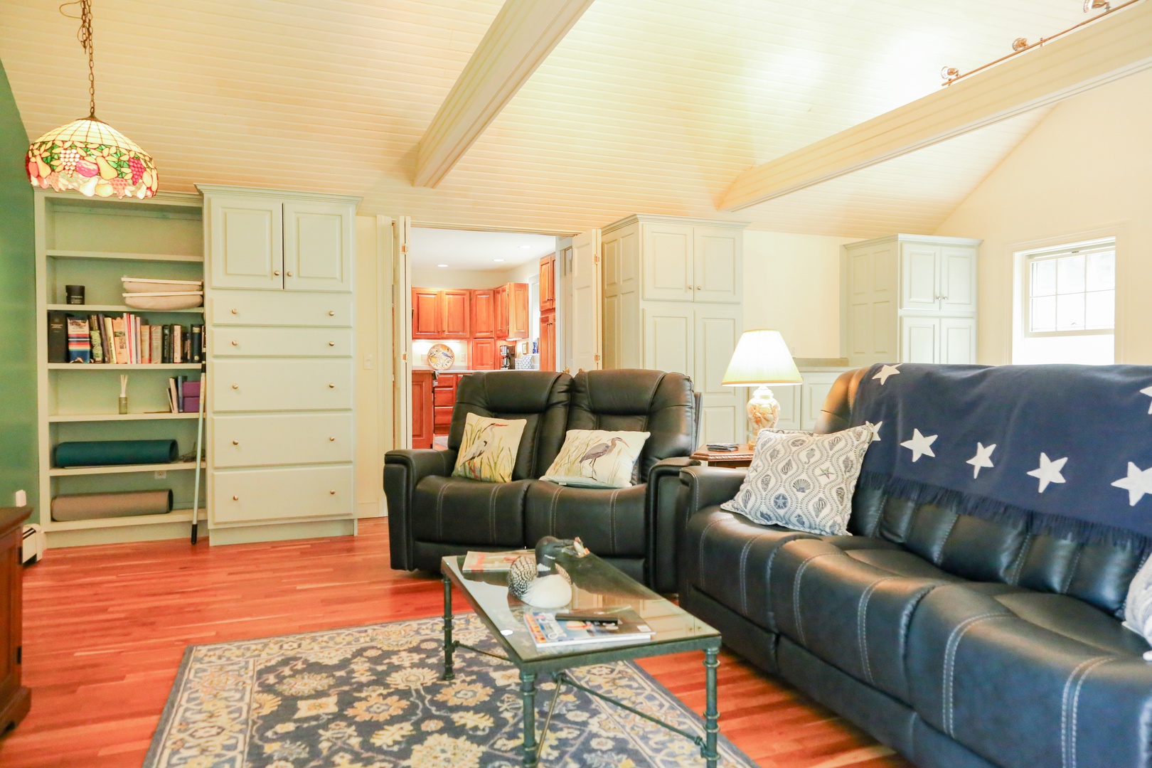 Settle into plush leather recliners in your private living room, where built-in bookshelves, warm wood tones, and thoughtful coastal touches create the perfect space to unwind after exploring.