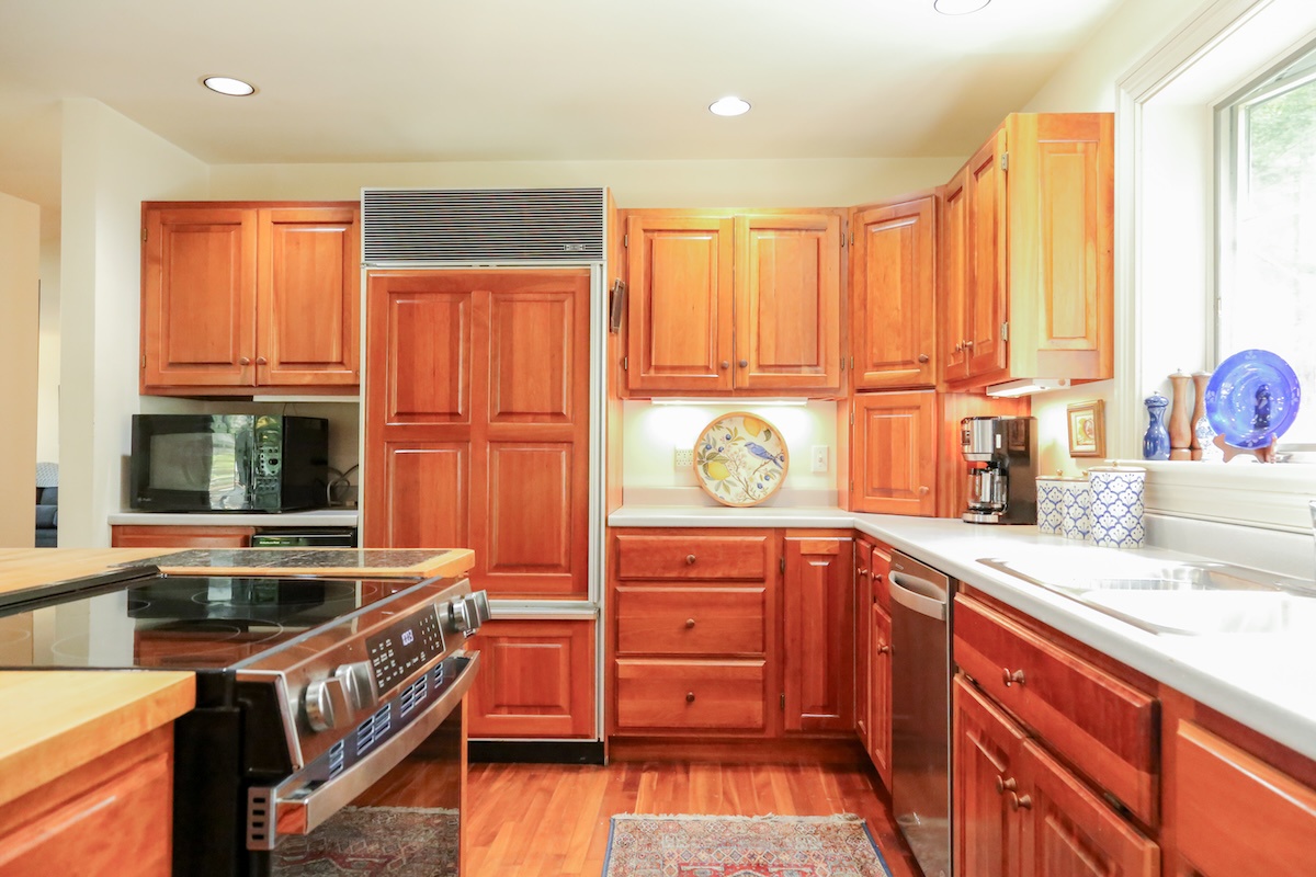 This well-appointed kitchen invites you to cook and gather with its warm cherry cabinetry, gleaming white counters, and modern stainless-steel appliances. Natural light floods in, making meal prep feel effortless and enjoyable.