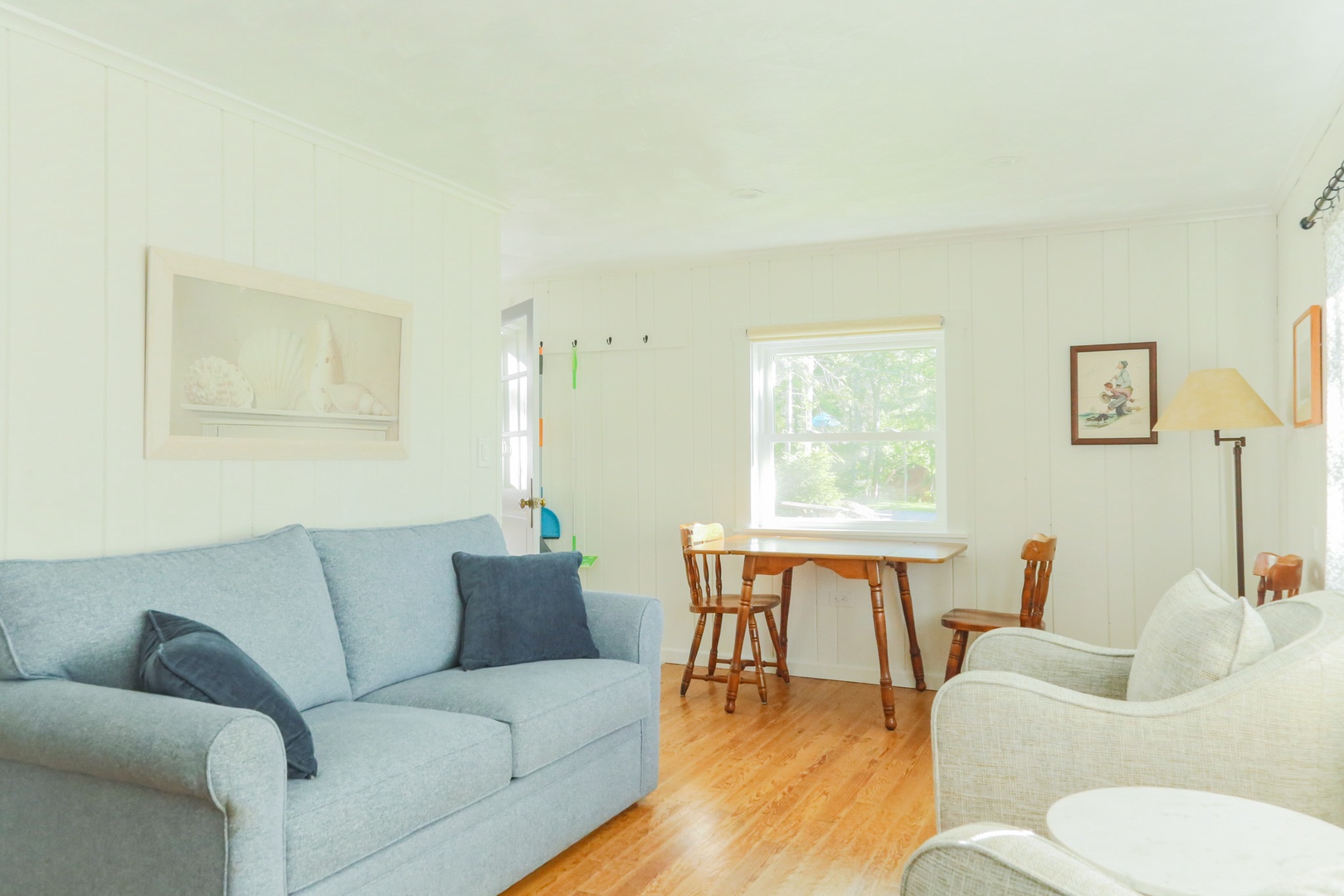 Sink into the cozy sofa and unwind in your bright, tranquil living space. Natural light streams through the window, highlighting warm wood floors and charming details that make this room feel like home.