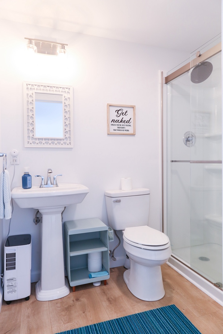 This bright bathroom features everything you need for a refreshing stay—a spacious shower, modern fixtures, and thoughtful touches like fresh towels and handy storage.