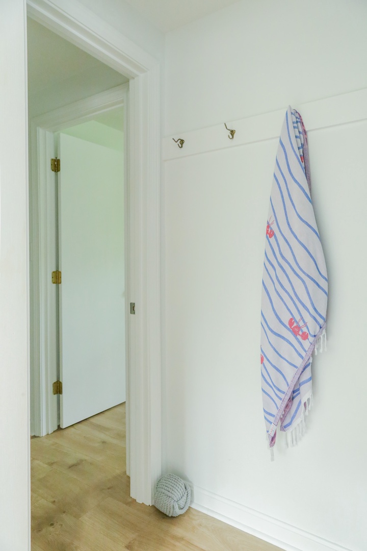 Step inside and make yourself at home—hang your beach towel on the hooks after a relaxing day by the water. Light wood floors and clean white walls create a bright, airy welcome.