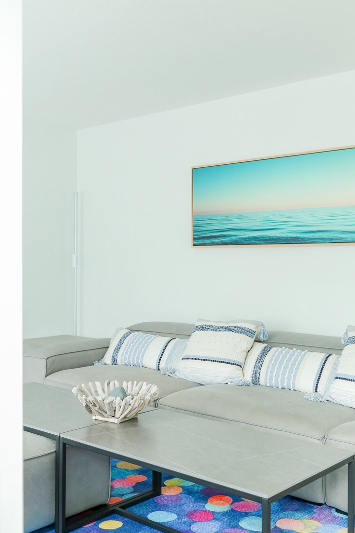 Sink into the plush sectional and feel the coastal calm wash over you. The serene palette and beachy accents create your perfect retreat after a day of exploring.