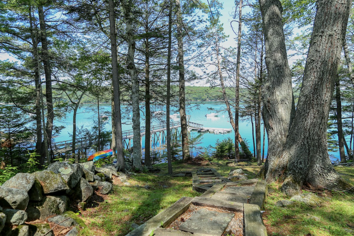 Wooded pathway leading down to a private waterfront dock, perfect for kayaking and soaking in serene water views surrounded by tall trees and natural beauty.