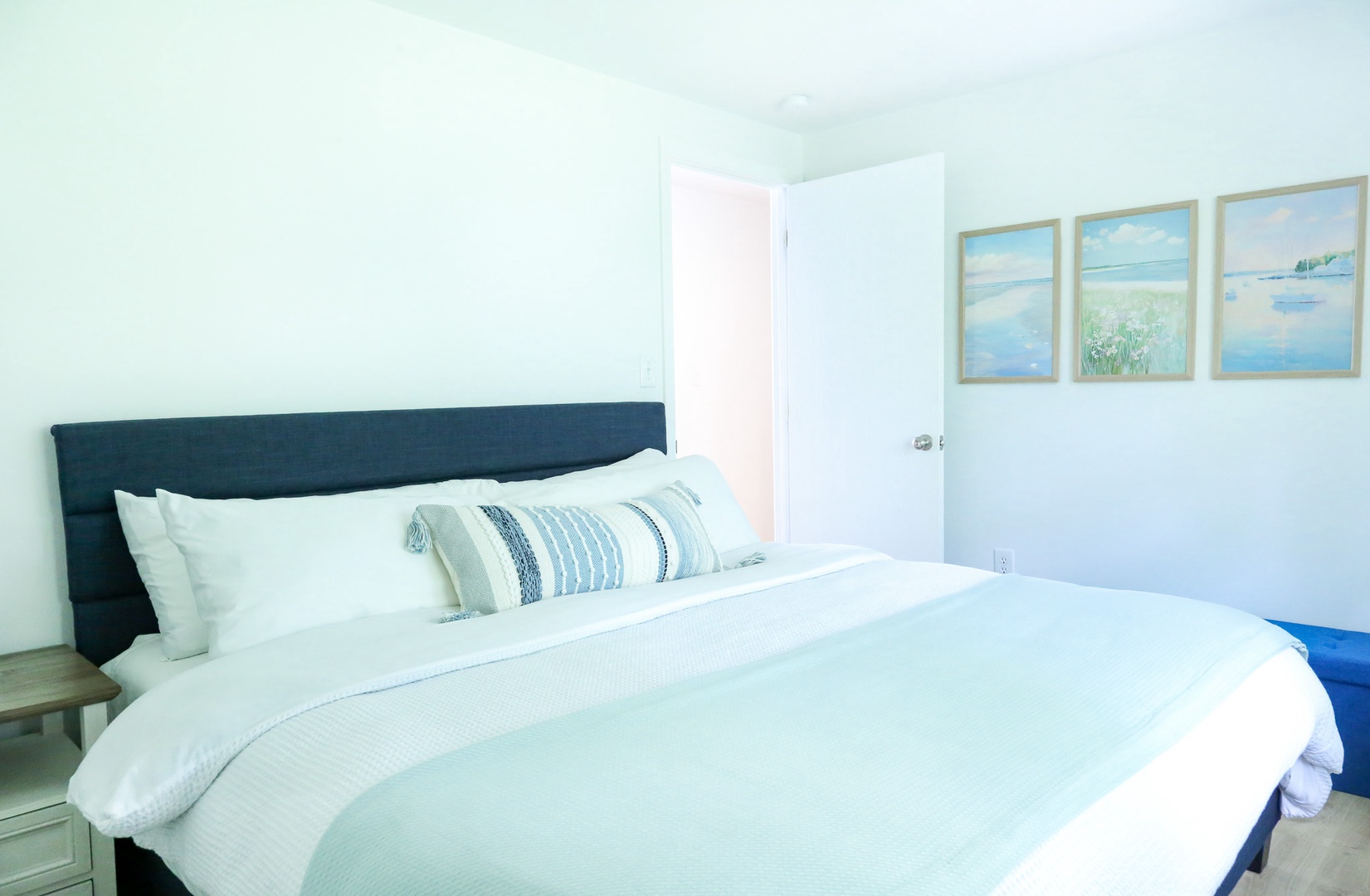 Drift off in your serene coastal bedroom with crisp linens, calming sea-blue tones, and gentle natural light welcoming restful nights.