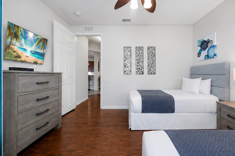 Drift off in crisp white linens while the ceiling fan gently circulates cool air through your peaceful twin bedroom retreat.