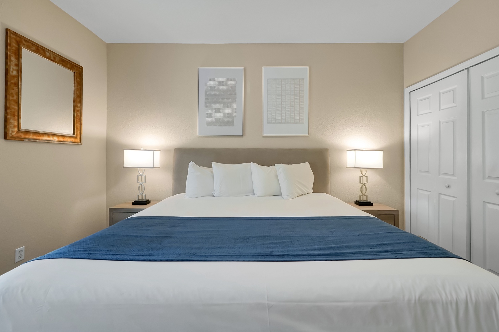Sink into crisp white linens with a stylish blue accent runner, perfectly framed by warm bedside lighting for your restful nights.