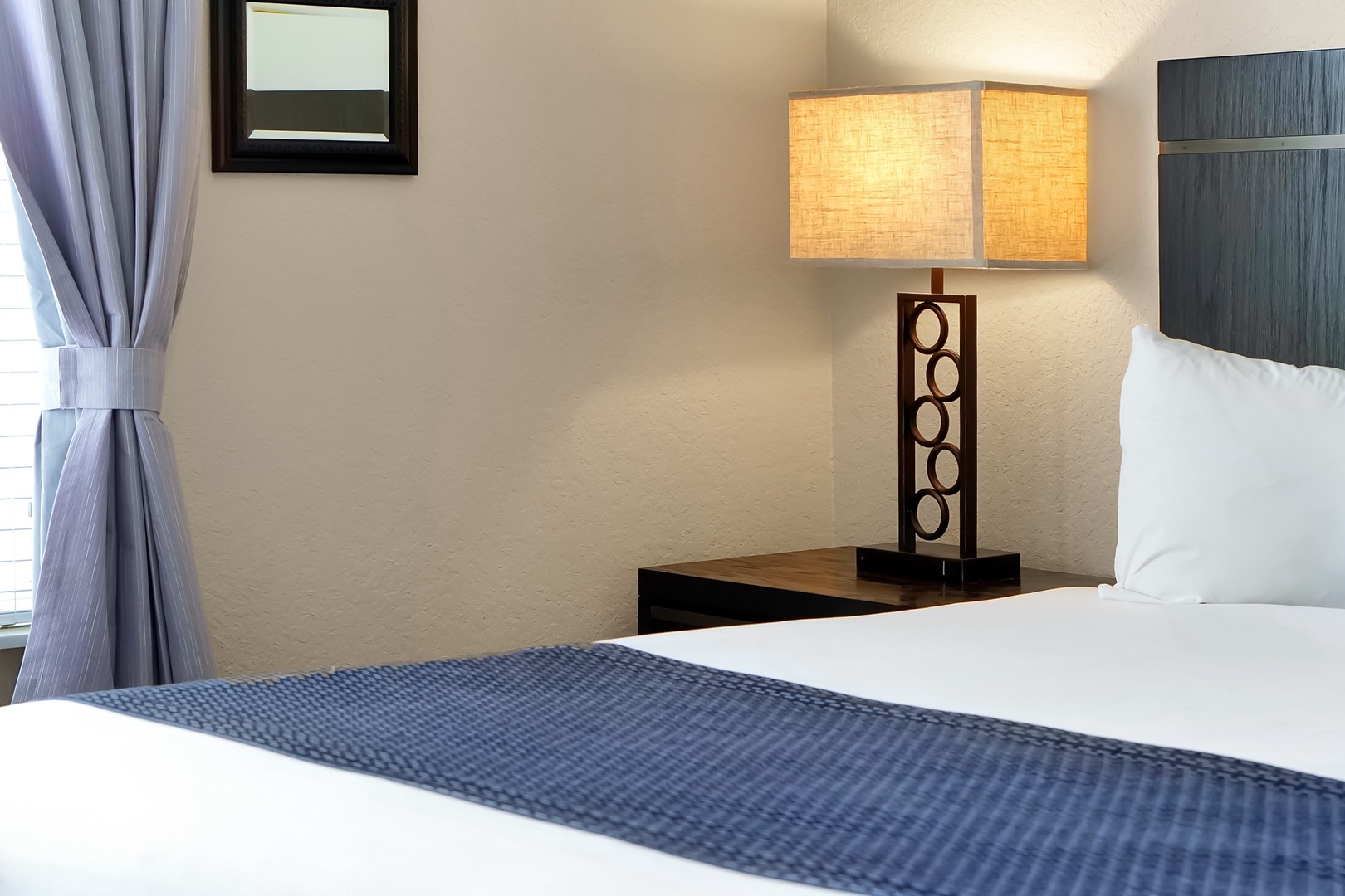 Sink into crisp white linens and unwind by the warm glow of your stylish bedside lamp.