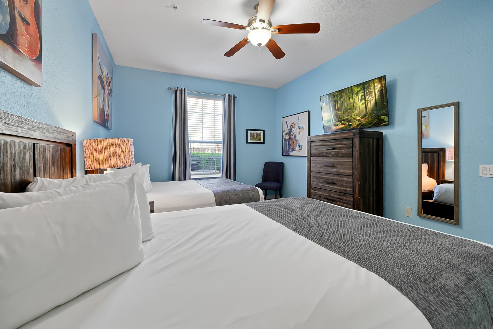 Relax in your tranquil twin bedroom with soft blue walls, comfortable bedding, and entertainment center for peaceful evenings.