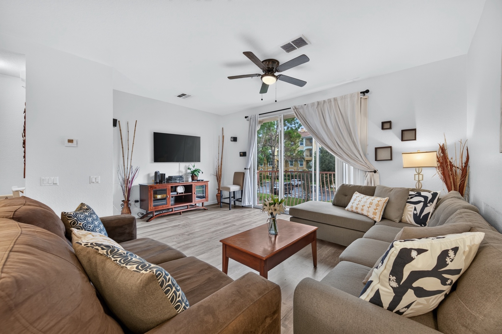 Your spacious living room welcomes you with soft seating, natural light streaming through sliding glass doors, and a ceiling fan to keep you comfortable—perfect for unwinding or gathering after your adventures.