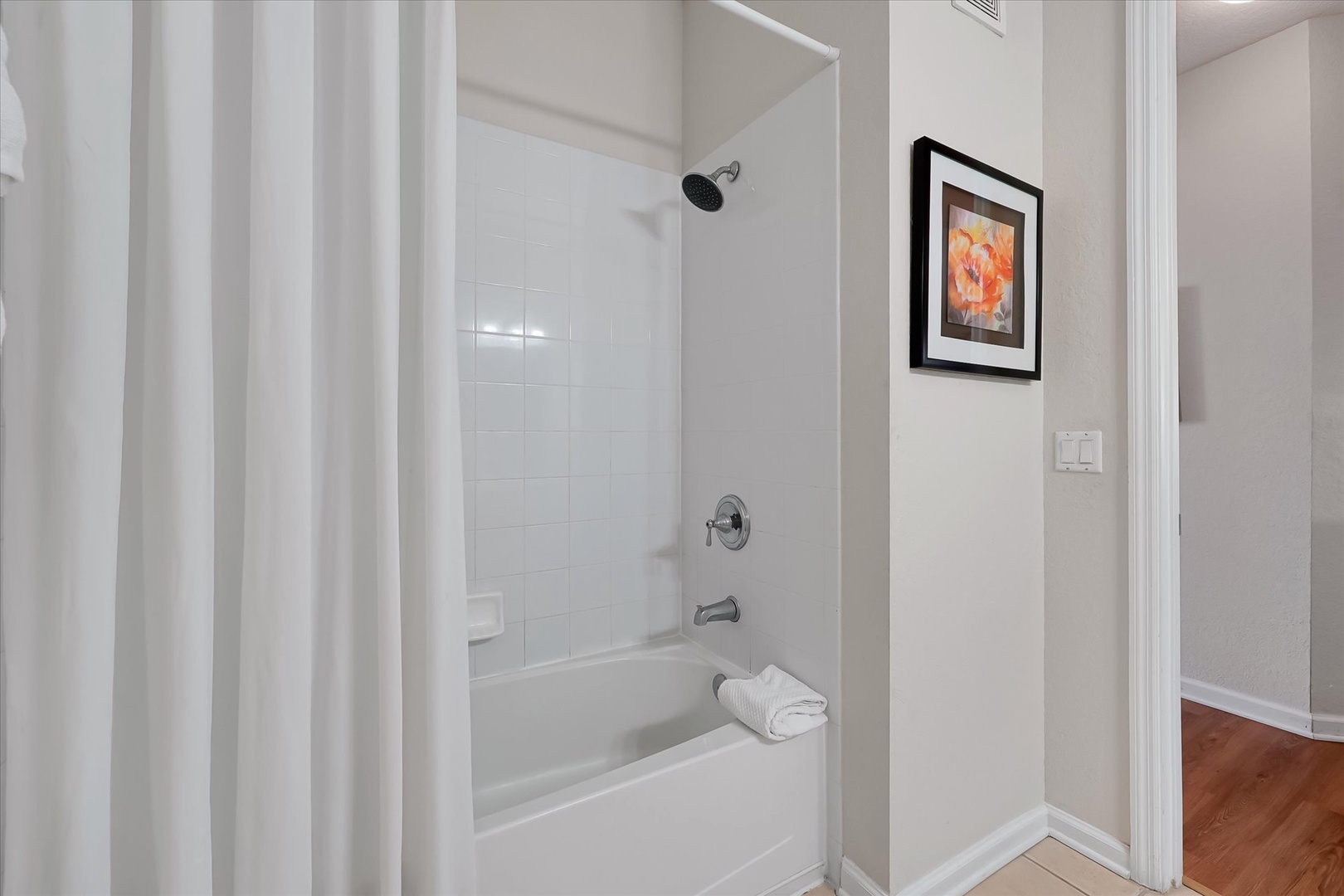 Your private bathroom features a pristine tub-shower combo with fresh towels waiting for you to unwind after exploring.