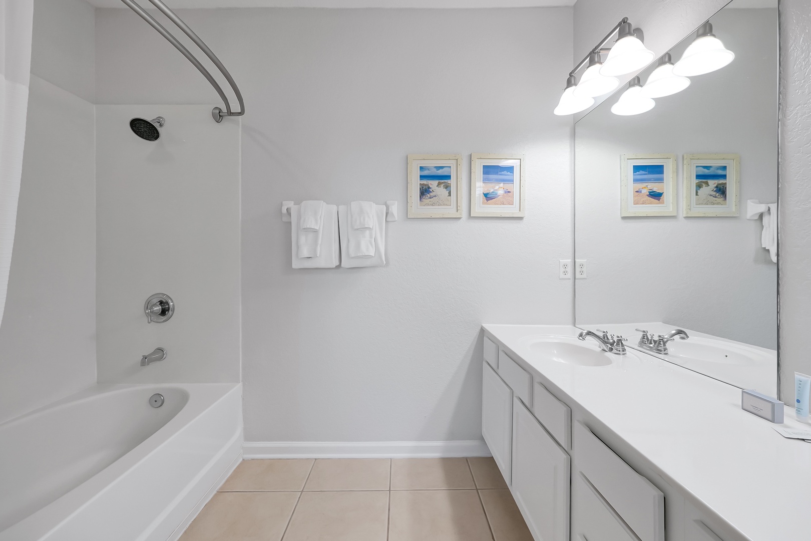 Freshen up in your spacious bathroom featuring a full tub-shower combo, dual sinks, and coastal artwork that brings beachside serenity to your daily routine.