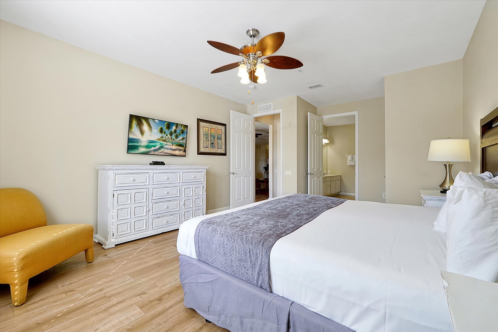 Sink into your comfortable bed under the gentle ceiling fan breeze, with spacious storage and bright coastal artwork creating your perfect retreat.