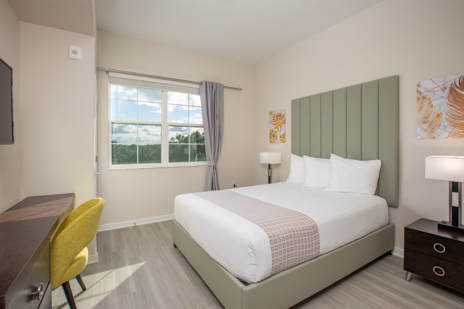 Unwind in your stylish bedroom featuring a plush queen bed, modern sage headboard, and serene treetop views through your private window.