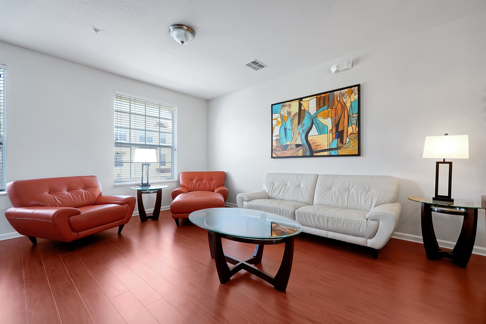 Sink into plush leather seating in your stylish living room, where vibrant artwork and warm hardwood floors create the perfect retreat.